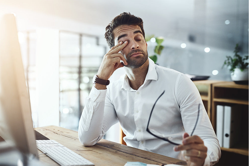 Very tired, low energy man sitting at a desk with a computer