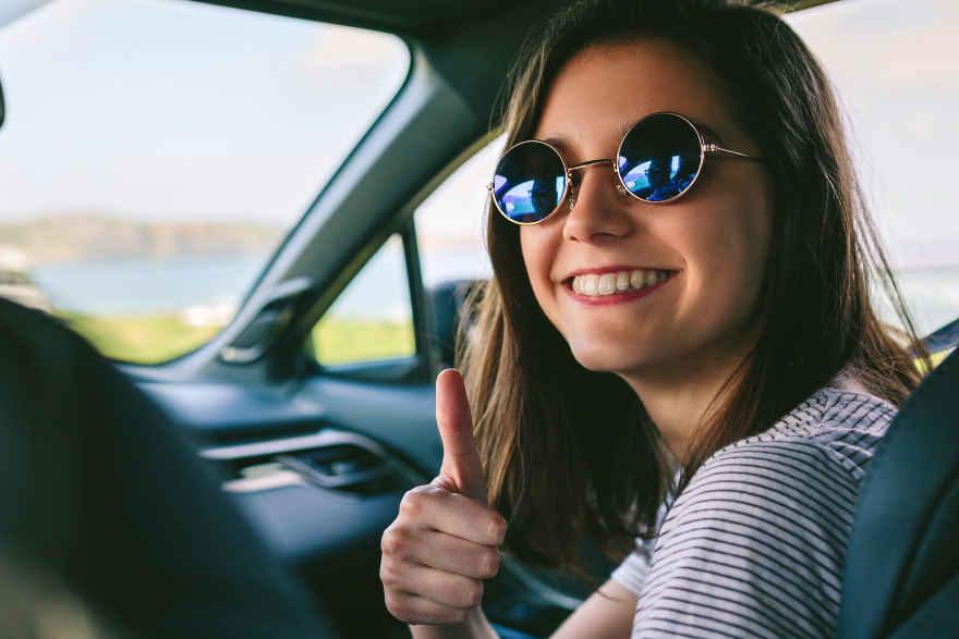 Girl giving thumbs up with sunglasses on sitting in the car