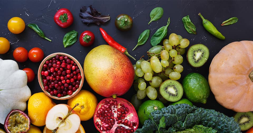 Many different fruits and vegetables on a black backdrop
