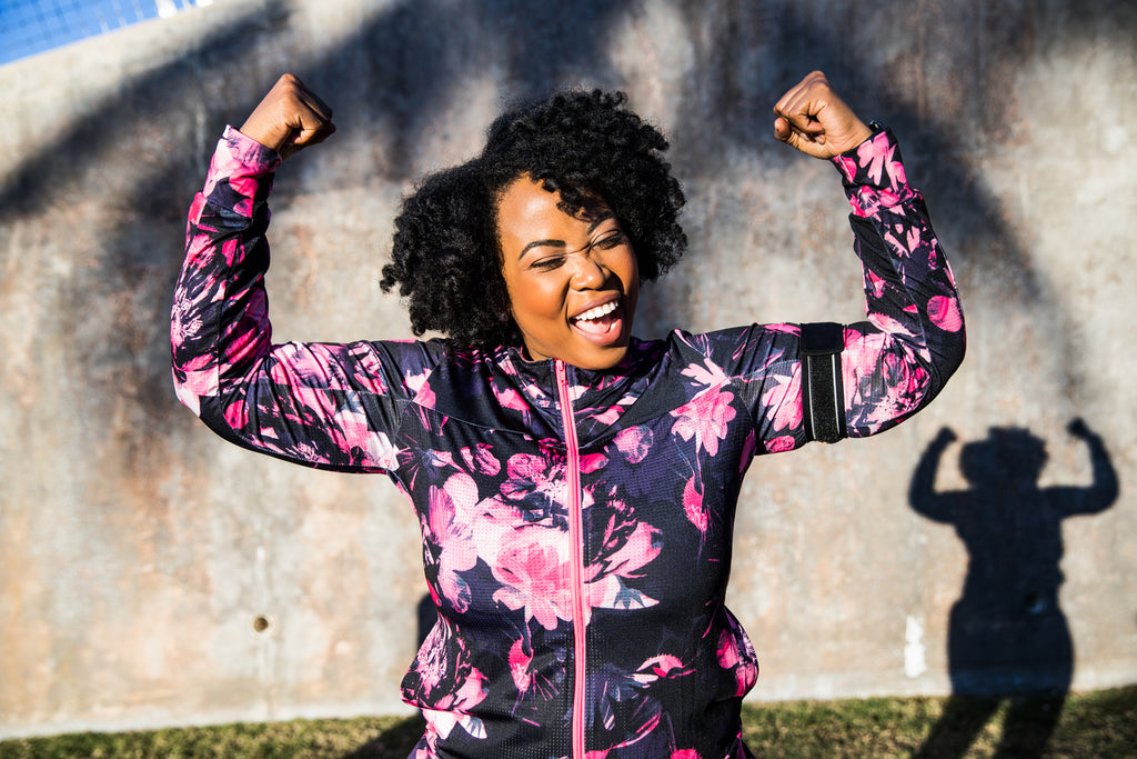 Black woman smiling while flexing her muscles