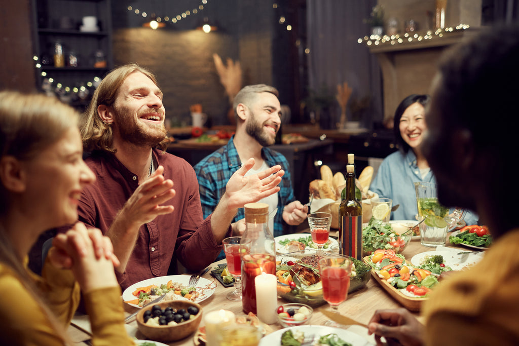 People laughing and eating a healthy meal with fruits and vegetables