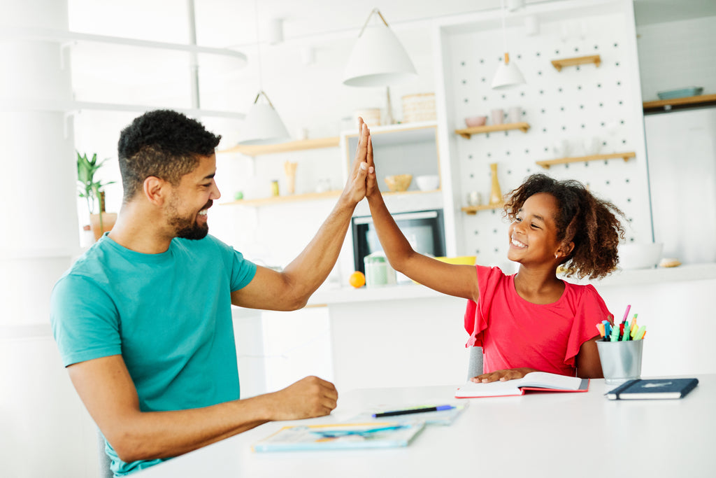 Dad high fiving his daughter helping her with homework