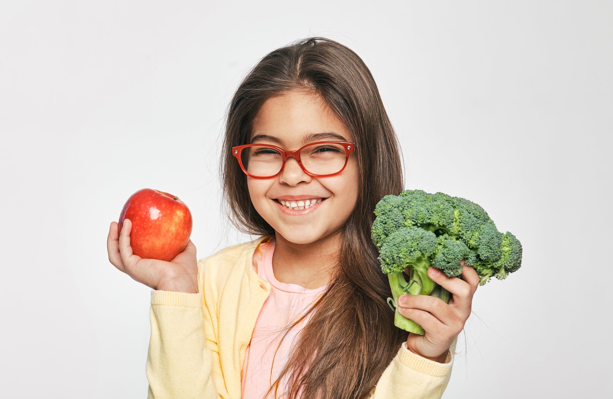 Girl holding fruits and veggies smiling