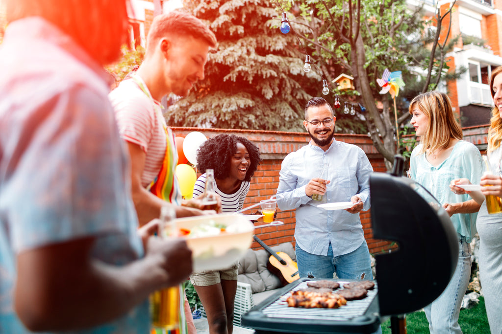 People having a 4th of july bbq laughing together outside with the sun shining
